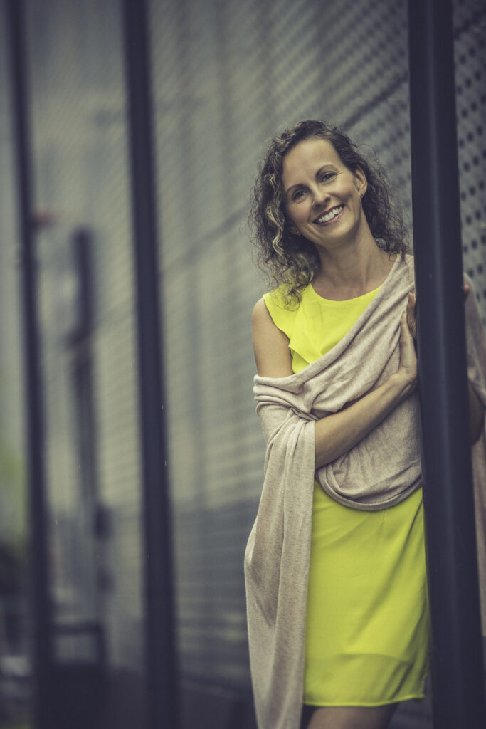 Kollases kleidis naine toetub vastu laternaposti ja vaatab kaamerasse